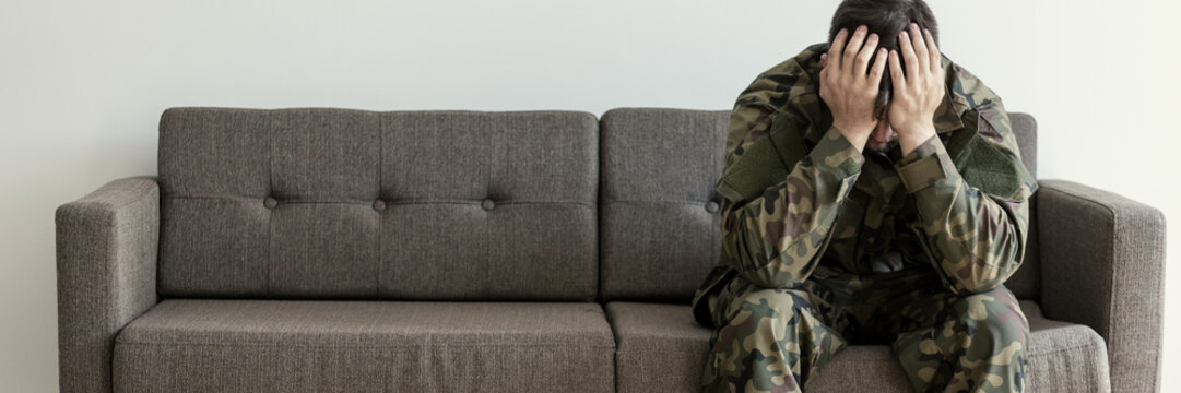 Soldier in uniform sitting on a sofa, waiting for his his appointment with a psychotherapist
