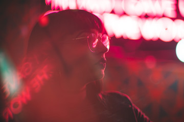 Young redhead dancer with glasses on neon lights