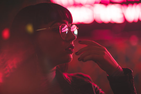 Young redhead dancer with glasses on neon lights