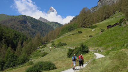 Fototapeta na wymiar Two Elderly Hikers in Mountain Landscape With Iconic Matterhorn Mountain in Distance