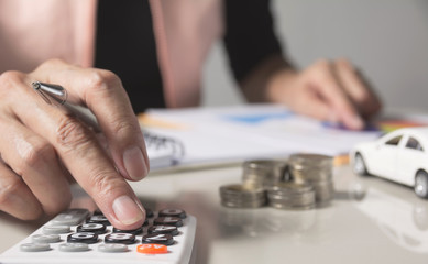 Car insurance and car service. Businesswoman with stack of coins and toy car, business and financial concept.