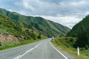 Road to the mountains, mountains, clouds and forest on the background