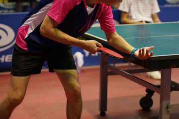 a pink shirt man is serving a ball during a table tennis game