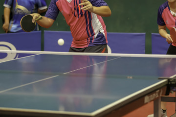a pink shirt man is forehand serving a ball during a table tennis game
