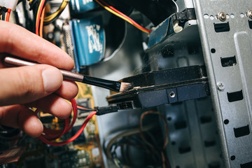 Inside details of the old personal computer. Motherboard and video card in the dust. Man is cleaning wires with a brush. Broken PC.