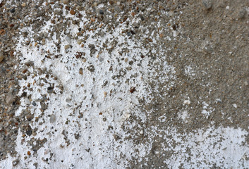 Background texture of a grey stone / cement wall with fading white paint on it.