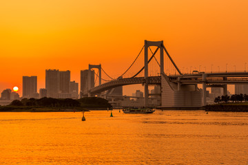 Tokyo skyline and rainbow bridge at sunset in Odaiba waterfront.