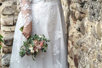 Beautiful plus size bride in the long sleeved dresswith flowers.Bridal morning details.