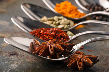 Various spices spoons and herbs on a rustic background