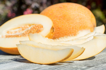 Whole and sliced melon on wooden table outdoors