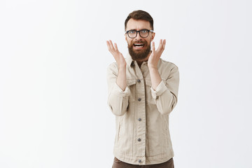 Pissed disstressed and annoyed adult hipster guy with long beard in black trendy glasses and beige...