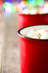 Christmas cocoa with marshmallow and Christmas lights background on wooden table

