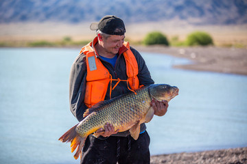 Obraz premium lucky fisherman holding a beautiful trophy fish