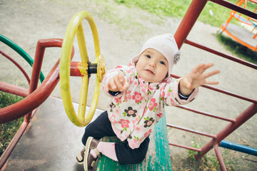 a ittle girl playing in the Playground. children's hand holding the steering wheel