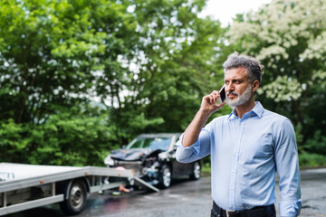 Mature man making a phone call after a car accident. Copy space.