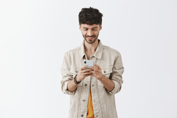 Checking updates of favorite app in smartphone. Portrait of creative good-looking european man with...