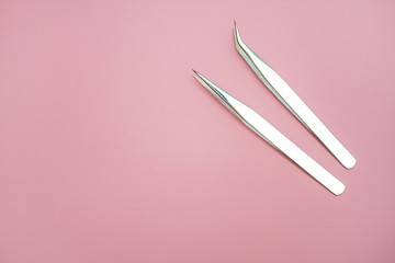 tools for Eyelash Extension Procedure. Two tweezers on pink background. copyspace mockup - Beauty...