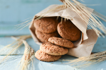 fresh oatmeal cookies in a bag made of paper on wooden background
