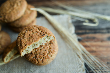 fresh homemade oatmeal cookies on wooden background with spikes of oats
