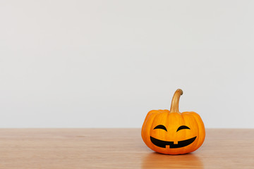 Pumpkin is smiling on wood table with white background. Halloween and decoration concept. Front view and copy space