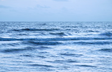 Naklejka na ściany i meble blurry sea water surf to beach on sunset