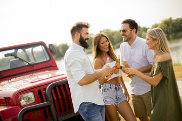 Young people drinking and having fun by car