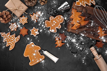 Woman decorating gingerbread Christmas cookies with icing sugar. Christmas preparations concept. Top view with copy space.