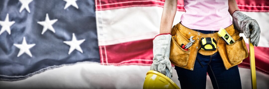 Composite image of woman with tool belt and holding hard hat