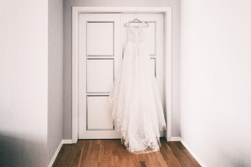 Fototapeta na wymiar wedding dress hanging on the door and waiting for the bride