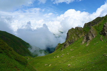 Fototapeta premium Hiking trail to Silver lakes with clouds around the mountains going via Tobavarchkhili from Mukhuri to Khaishi in Caucasus mountains, Georgia