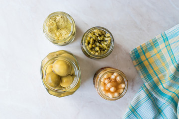 Jars of Pickled Vegetables Green and White Asparagus, Artichoke Heart and Unripe Green Almond Pickles in Glass Bottle.