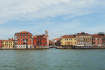 Venetian channel view at the city in one horizontal line of urban architecture, buildings, one of the Venice Bridge, free space