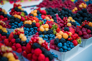 Fresh different berries in the plastic cup at Europe dong street berries and exotic fruits at market streetshop. Assortment festive appetizers in the cup, selective focus. - 220831812