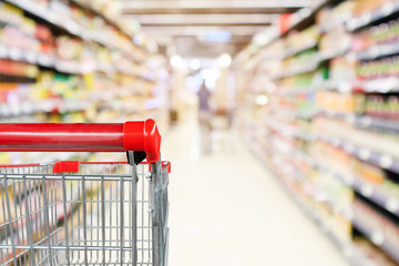 Empty shopping cart with abstract blur supermarket discount store aisle and product shelves...