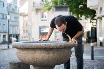 Caucasian young man preparing to drinking water from the fountain.