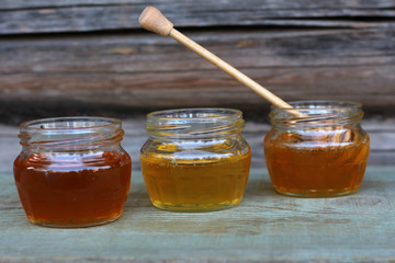 three cans of honey of different colors on wooden background