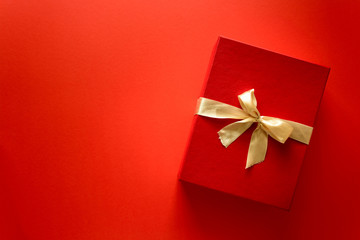 Top view on Christmas gifts wrapped in gift paper decorated with ribbon on red paper background. New Year, holidays and celebration decorations concept. Copy space. Flat lay