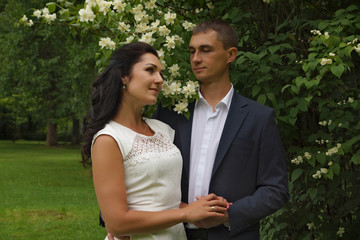 Fototapeta premium Beautiful brunette in white dress smiles next to her fiance