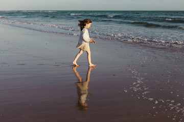 Girl on beach walking towards ocean, Spain