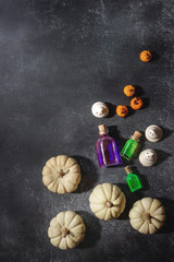 Halloween holiday decoration marzipan and decorative pumpkins, meringue ghosts, poison's bottles over black texture background. Flat lay, space