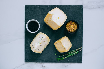 Assorted ?achotta cheese with black cumin, fenugreek and herbs on black shale
