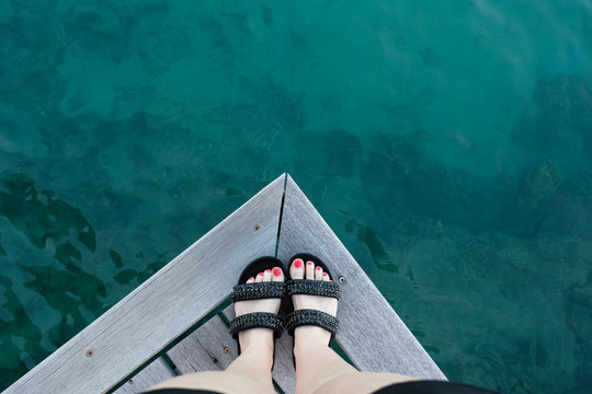 Close-up Of A Woman's Feet Standing On The Edge Of A Wooden Jetty, Tahiti, French Polynesia