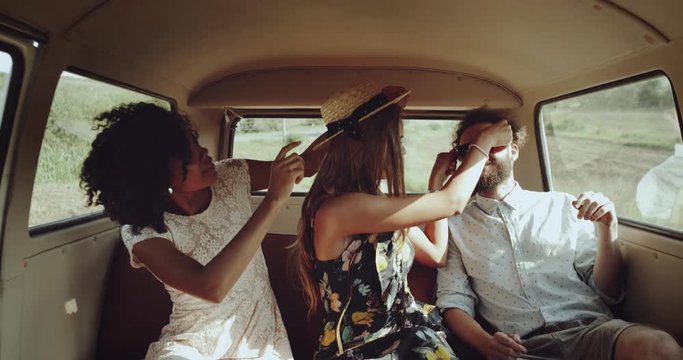Two young women and one man inside of retro bus spending nice time together smiling faces wearing boho style clothes. Slow Motions