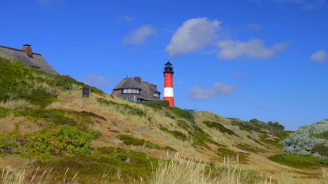 Leuchtturm H&ouml;rnum Sylt mit D&uuml;nen Landschaft  Reetdach H&auml;usern und  blauen Himmel
