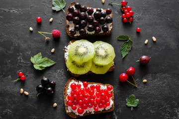 homemade sandwiches with berries and fruits on a black background