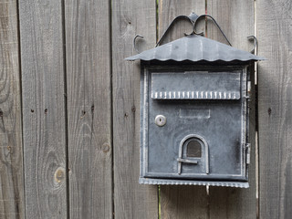 Forged metal mailbox on a wooden fence