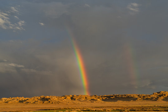 Storm clouds and a rainbow at sunset, Baga Gazariin Chuluu, Mongolia