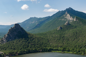 Beautiful mountains covered with pine forest on the shore of the lake.