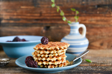 Round waffles with fresh blackberries and whipped cream, on natural wooden background in rustic style
