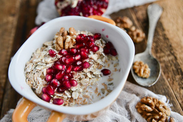 Breakfast: granola with pomegranate and walnuts on natural wooden background rustic. The concept of healthy and high-carbon nutrition.